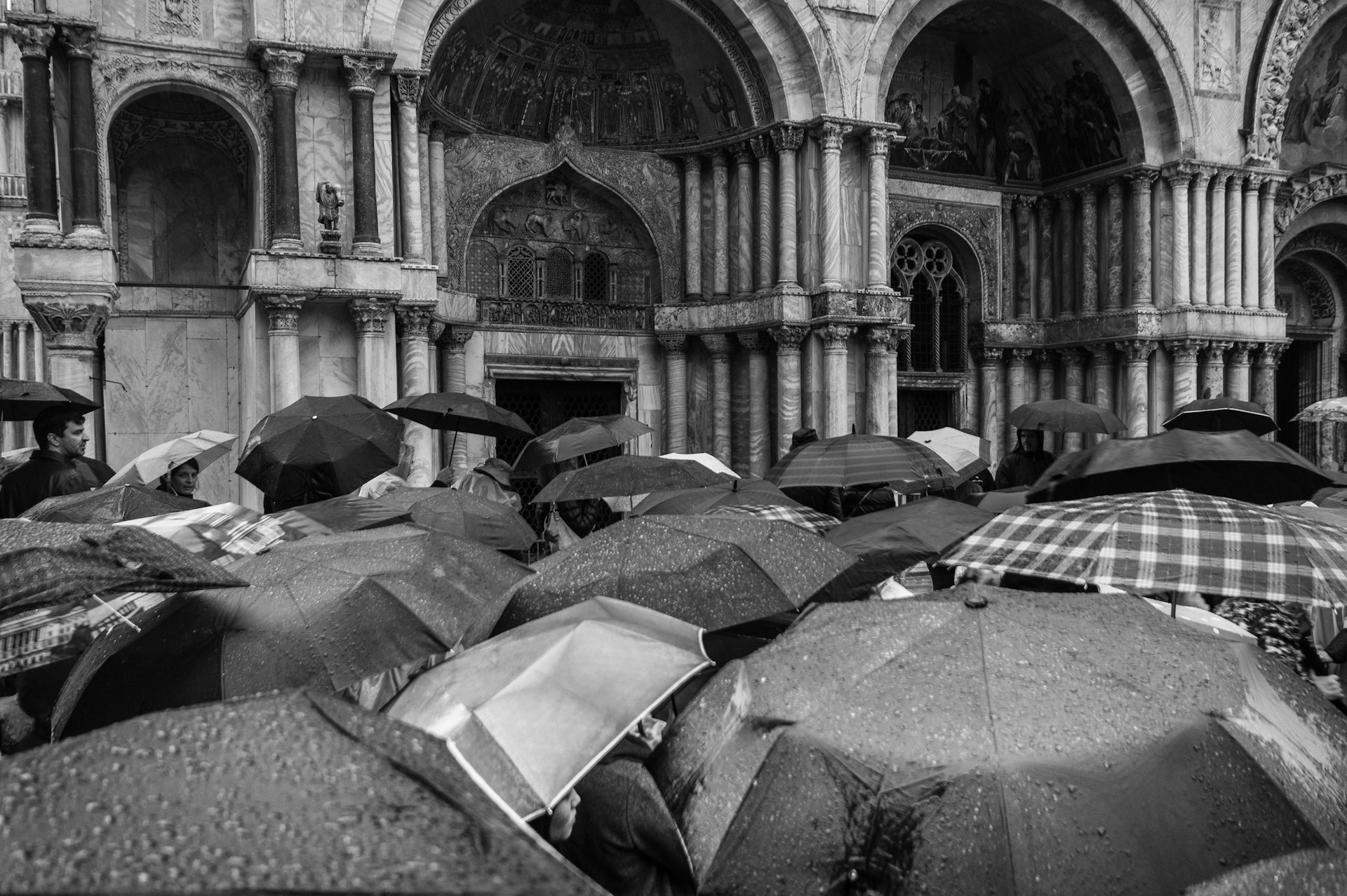 Image en noir et blanc de nombreux parapluies devant une église.